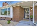 Close-up of a brick home entrance with a bay window, decorative door wreath and manicured landscaping at 10340 W 34Th Ave, Wheat Ridge, CO 80033