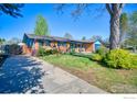Charming single-story home with a brick exterior, lush lawn, and a cozy covered porch at 19 University Cir, Longmont, CO 80503