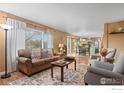 Spacious living room boasts large window, brown sofa, armchairs, and open to the kitchen and dining area at 2085 E 127Th Pl, Thornton, CO 80241