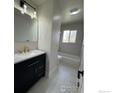 Modern bathroom featuring a sleek vanity with black cabinets, gold fixtures, and stylish tiled floors at 2221 E 84Th Ave, Denver, CO 80229