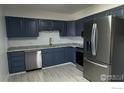 Updated kitchen features stainless steel appliances, granite counters, and stylish blue cabinets at 2221 E 84Th Ave, Denver, CO 80229