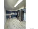 Spacious kitchen featuring stainless steel refrigerator, blue cabinets, and wood-look flooring at 2221 E 84Th Ave, Denver, CO 80229