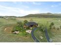 Idyllic aerial view of a home with a circular driveway surrounded by mature trees and open land at 6319 Sedona Hills Dr, Berthoud, CO 80513