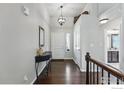 Inviting entryway with dark wood floors, elegant lighting fixture, and decorative table at 725 Canyonlands St, Berthoud, CO 80513