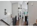 Well-lit hallway with hardwood floors, decorative wall sconces, and staircase at 725 Canyonlands St, Berthoud, CO 80513
