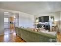 Open living room features gleaming wood floors, a comfortable green couch, and contemporary décor at 8200 Delaware St, Denver, CO 80221
