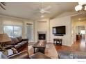 Open living room showcasing a fireplace, hardwood floors, leather furniture, and a large flat-screen TV at 8255 E 150Th Pl, Thornton, CO 80602