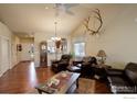 Inviting living room with vaulted ceilings, hardwood floors, leather furniture, and a decorative elk skull at 8255 E 150Th Pl, Thornton, CO 80602