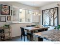 Dining area with rustic wooden table, modern light fixture, shuttered window, and framed art, perfect for entertaining at 1069 Johnson Ln, Louisville, CO 80027