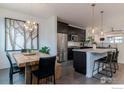 Open-concept kitchen and dining area with stainless steel appliances, a granite island, and a rustic wooden dining table at 1069 Johnson Ln, Louisville, CO 80027