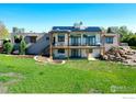 Rear exterior of a two-story home with a deck, patio, solar panels, and landscaped backyard at 11251 Lookout Dr, Longmont, CO 80504