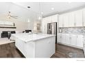 Bright, open kitchen features white cabinets, an island, and stainless steel appliances at 11500 E 162Nd Dr, Brighton, CO 80602