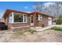 Inviting brick home featuring a large front window, covered porch, and well-kept landscaping at 1153 Lincoln St, Longmont, CO 80501