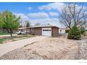 A single-story brick home with an attached garage, and a well-maintained yard on a sunny day at 1153 Lincoln St, Longmont, CO 80501
