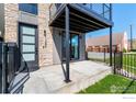 Covered patio area with modern townhome showcasing stone accents and black metal balcony at 1385 N King St, Denver, CO 80204
