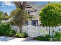 Two-story home with blue shutters and a white picket fence, complemented by lush landscaping, offering inviting curb appeal at 1503 Balsam Ave, Boulder, CO 80304