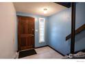 Inviting home foyer featuring a wood front door, decorative glass block window, and a staircase leading to the upper level at 1937 Meadow Dr # A7, Longmont, CO 80501