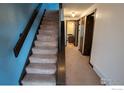 Carpeted staircase with wooden banister, and view of a hallway leading to additional rooms in the house at 1937 Meadow Dr # A7, Longmont, CO 80501