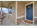 Inviting entryway featuring a blue front door, a welcome mat, stone accents, and a cozy porch at 5478 Teton Dr, Longmont, CO 80504