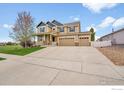 Well-maintained two-story home with a large driveway, a lush lawn, and a three-car garage at 5478 Teton Dr, Longmont, CO 80504