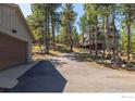 Long driveway leading up to a mountain home, lined with trees and a detached garage at 65 Bristlecone Way, Boulder, CO 80304