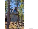 A-frame home with a balcony, surrounded by pine trees and a rocky landscape at 65 Bristlecone Way, Boulder, CO 80304