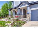 Inviting home entrance featuring stone accents, landscaped garden beds, and a charming covered porch area at 910 Pope Dr, Erie, CO 80516