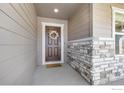 Inviting front entrance featuring a wreath-adorned door, decorative stone detail, and fresh paint at 922 Colorado River Ave, Brighton, CO 80601