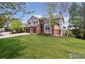 Charming two-story house featuring a lush green lawn and mature trees in a suburban setting at 14100 Doral Ct, Broomfield, CO 80023