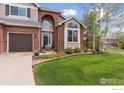Attractive home featuring manicured landscaping, a brick facade, and a well-kept lawn at 14100 Doral Ct, Broomfield, CO 80023
