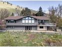 Rear exterior featuring multiple windows and doors, deck, and beautiful landscaping on a lush hillside at 230 Cactus Ct, Boulder, CO 80304