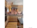 Modern kitchen with wooden cabinetry, stainless steel appliances, and a vibrant backsplash at 230 Cactus Ct, Boulder, CO 80304