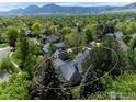 Beautiful aerial view of a suburban home surrounded by lush greenery and mature trees, with mountains in the background at 2672 Winding Trail Dr, Boulder, CO 80304