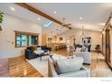 Open living room features vaulted ceilings, exposed beams, hardwood floors, and access to dining and kitchen at 5604 Bowron Pl, Longmont, CO 80503