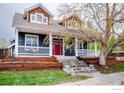Beautiful home featuring a welcoming front porch, tiered garden beds, and lush green lawn at 945 Lincoln Ave, Louisville, CO 80027
