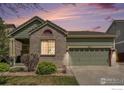 Charming one-story home with green siding, brick accents, landscaped front yard and a two car garage at dusk at 9674 Joplin St, Commerce City, CO 80022