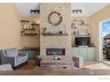 Cozy living room boasts a stone fireplace, modern lighting and floating shelves, creating a warm, inviting space at 111 Hunters Cove Rd, Mead, CO 80542