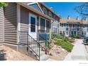 Exterior view of a well-maintained townhome with a welcoming entrance, landscaping, and a convenient sidewalk at 11590 Community Center Dr # 44, Northglenn, CO 80233