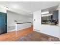 Open-concept living room with hardwood and carpet floors, leading to a pass-through kitchen bar and outside access at 11590 Community Center Dr # 44, Northglenn, CO 80233