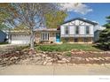 Charming two-story home with a well-manicured front yard, beautiful landscaping, and a bright blue front door at 1309 Alexandria St, Lafayette, CO 80026