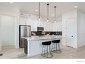 Bright kitchen featuring a large island, stainless steel refrigerator, and sleek white cabinetry with pendant lights at 1581 Poplar Dr, Erie, CO 80516
