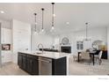 Open concept kitchen, living, and dining area featuring a modern island, fireplace, and hardwood floors at 1581 Poplar Dr, Erie, CO 80516