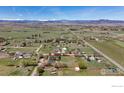Aerial view of a home on a large lot, surrounded by fields and distant mountains at 1720 Chaparro Cir, Berthoud, CO 80513
