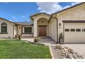 A well-maintained front yard leads to a custom wood front door and three-car garage at 1720 Chaparro Cir, Berthoud, CO 80513