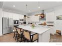 Bright kitchen with white cabinets, stainless steel appliances, a large center island and bar stool seating at 2482 Claystone Cir, Erie, CO 80516