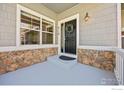 Inviting front porch showcasing stone accents and a stylish black front door with decorative wreath at 4119 Riley Dr, Longmont, CO 80503