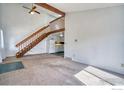 Open-concept living space features carpet, staircase, view into kitchen with white appliances and cabinets at 607 5Th St, Frederick, CO 80530