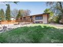 Well-maintained home with mature trees, a landscaped yard, and a spacious deck at 7240 Glacier View Rd, Longmont, CO 80503