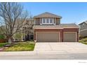 Inviting two-story home featuring a brick facade, three-car garage, and well-manicured lawn at 10305 Charissglen Cir, Highlands Ranch, CO 80126