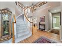 Grand foyer showcasing a curved staircase, hardwood floors, and an elegant chandelier, creating a welcoming entrance at 10305 Charissglen Cir, Highlands Ranch, CO 80126